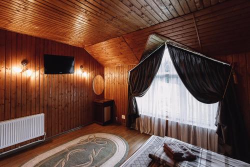 1 dormitorio con ventana grande y paredes de madera en Toga en Yablunytsya