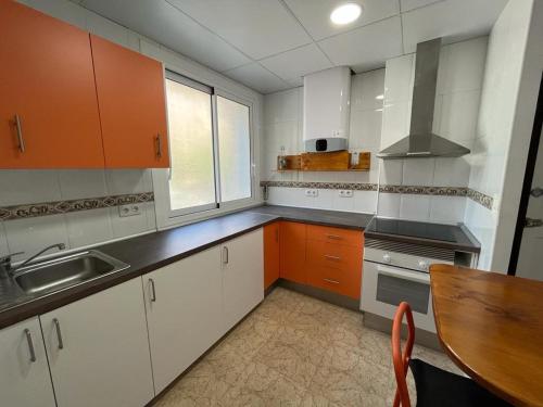 kuchnia z pomarańczowymi i białymi szafkami oraz stołem w obiekcie Casa Blanca w Murcji