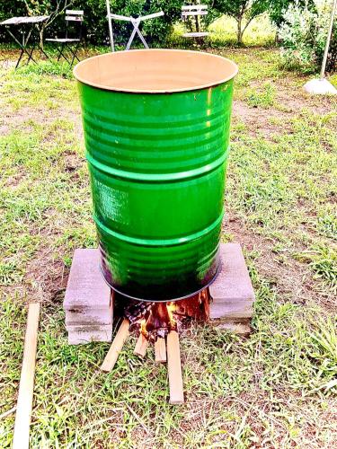 a green barrel sitting on a fire in the grass at 竜野園藝 in Kamimashiki