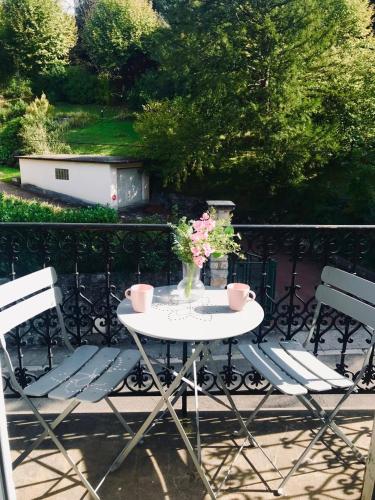 une table blanche avec deux chaises et un vase de fleurs dans l'établissement Charmant studio proche du centre et des thermes, à Aix-les-Bains