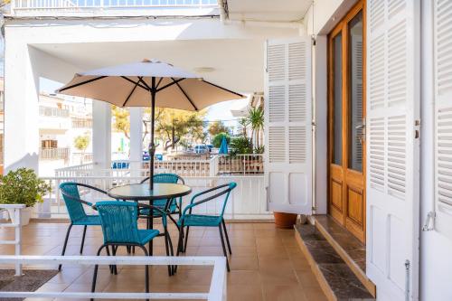 un patio avec une table, des chaises et un parasol dans l'établissement Can Miquel, à Can Picafort