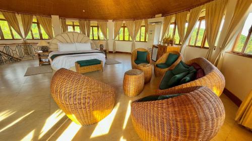 Coco Grove Beach Resort, Siquijor Island في سيكويجور: غرفة نوم مع سرير وكراسي الخوص
