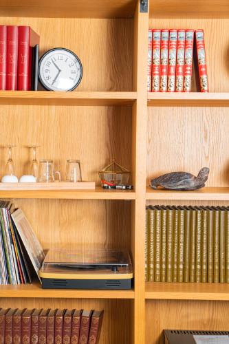 a book shelf with a clock and books at En Marge in Aureville