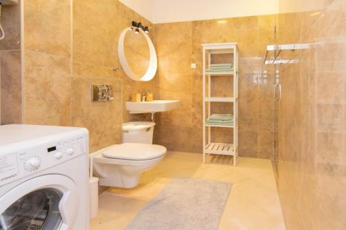 a bathroom with a toilet and a shower and a washing machine at Bliss on the Bay in Njivice