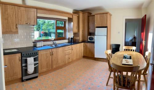 una cocina con armarios de madera y una mesa. en Lily's - 3 Bedroom Country Cottage with Large Garden, en Sligo