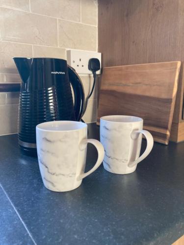two cups sitting on a counter next to a coffee pot at Lily's - 3 Bedroom Country Cottage with Large Garden in Sligo