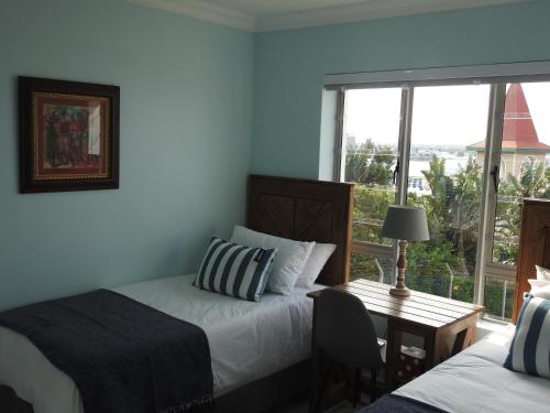 1 dormitorio con 2 camas, escritorio y ventana en Marina Sands 13A, en Jeffreys Bay