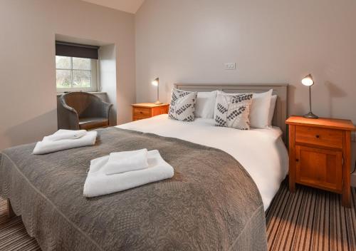 a bedroom with a large bed with two towels on it at Geufron Barn in Aberdaron