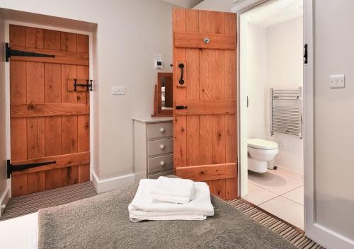 a bathroom with a toilet and a wooden door at Geufron Barn in Aberdaron