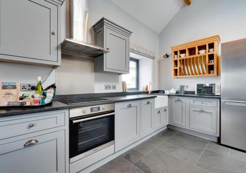 a kitchen with white cabinets and stainless steel appliances at Gwêl y Grib in Pen-y-groes
