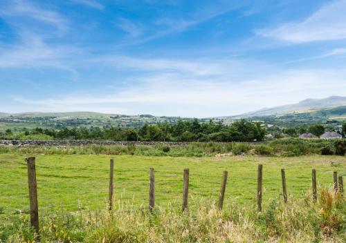 a fence in a field with mountains in the background at Gwêl y Grib in Pen-y-groes