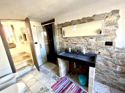 a bathroom with a sink and a stone wall at Lu Chiapparu - Vacanza Low Cost in Lequile