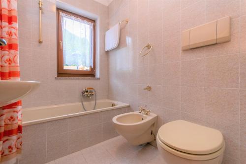 a bathroom with a toilet and a tub and a sink at Ciasa Molino 306 in Falcade
