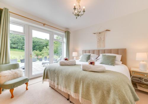 a bedroom with two beds and a chair and a window at Nyth Bryn Haul in Llanidloes