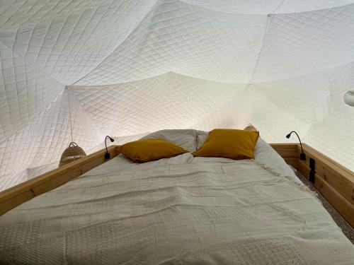 a white bed with two yellow pillows on it at beGLAMP - Glamping nad Zalewem Próba in Brzeźnio