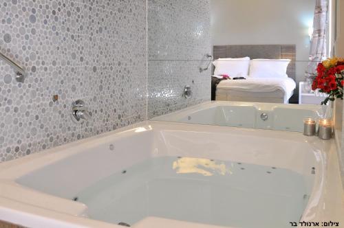 a white bath tub in a bathroom with a bedroom at Etnachta Kibbutz Afik in Afik