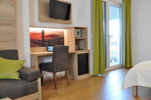 salon z biurkiem, telewizorem i kanapą w obiekcie Seehotel Herlinde w mieście Podersdorf am See