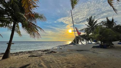 a boat sitting on the beach with the sun setting at Coco Grove Beach Resort, Siquijor Island in Siquijor