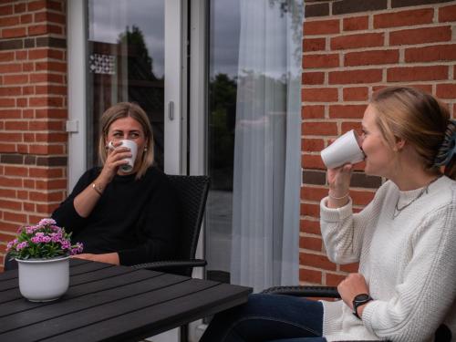 two women sitting at a table drinking cups of coffee at Hotel Søgården Brørup in Brørup