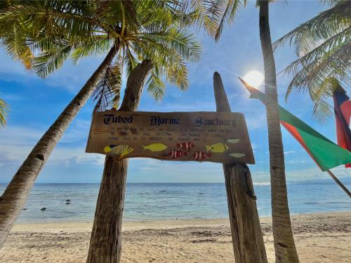 a sign on a beach with palm trees and the ocean at Coco Grove Beach Resort, Siquijor Island in Siquijor