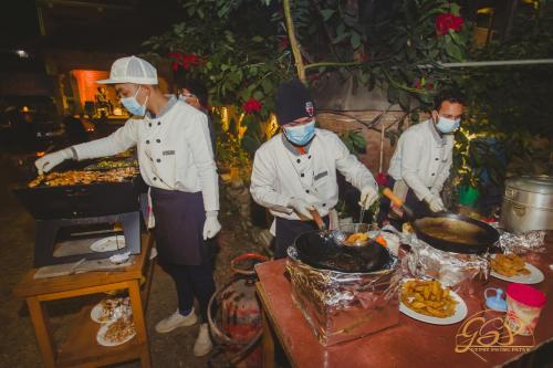 grupa trzech kucharzy przygotowujących jedzenie na stole w obiekcie Yalamul Garden w mieście Patan