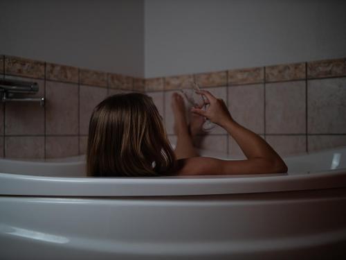 a woman is sitting in a bath tub at Hotel Søgården Brørup in Brørup