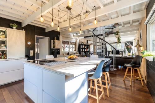 une cuisine avec des placards blancs et un grand îlot avec des tabourets de bar dans l'établissement Maison à 500 m de l'océan Carcans, à Carcans