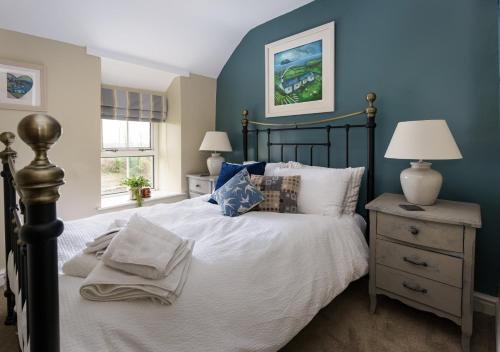 a bedroom with a large bed with blue walls at Marina Beach Cottage in Pwllheli