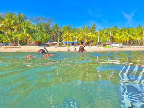 a group of people swimming in the water at a beach at Coco Grove Beach Resort, Siquijor Island in Siquijor