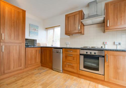 uma cozinha com armários de madeira e um forno com placa de fogão em The Cross - Y Groes em Oxwich