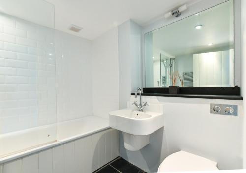 Baño blanco con lavabo y espejo en Pengarth Cottage, en Abersoch