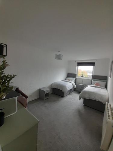 Habitación blanca con 2 camas y ventana en Whole Apartment with Balcony Breakfast & Parking en Bishop Auckland
