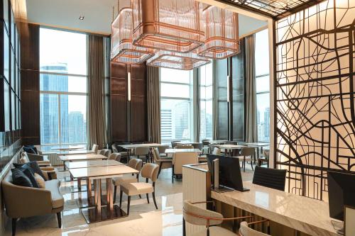a restaurant with tables and chairs and large windows at Le Meridien Bangkok in Bangkok