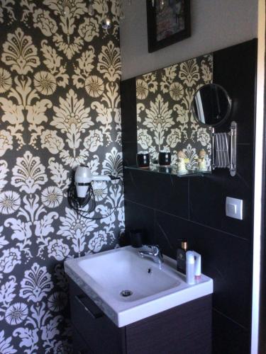 un bagno con lavandino e carta da parati in bianco e nero di L’hirondelle du Faubourg 