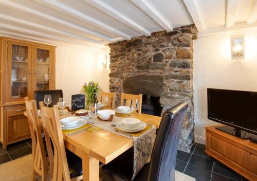 une salle à manger avec une table en bois et une cheminée dans l'établissement Ty Hen, à Capel Celyn