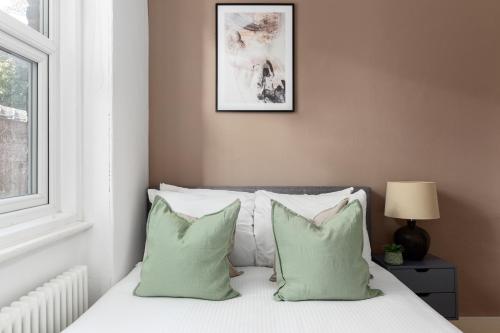a bedroom with a bed with green and white pillows at The Goldhawk Road Apartments in London