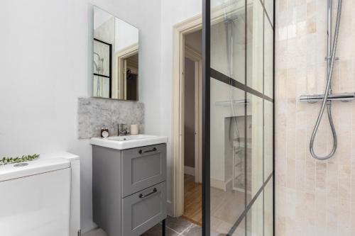a bathroom with a shower and a sink and a mirror at The Goldhawk Road Apartments in London