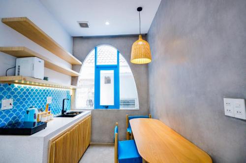 a kitchen with a wooden table and a window at Tò Vò Hostel Huế in Hue