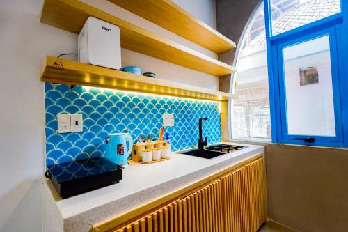 a kitchen with a counter with a sink and a window at Tò Vò Hostel Huế in Hue