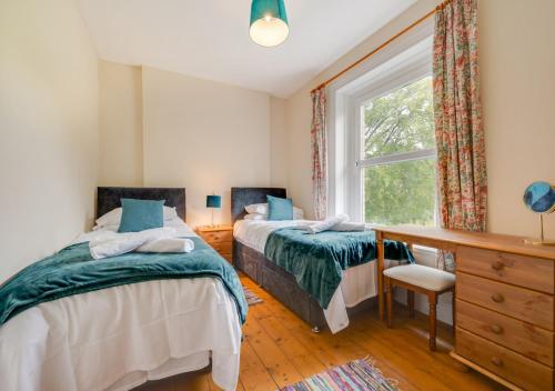 a bedroom with two beds and a window at Greengrove Farmhouse Glasallt in Llangadog