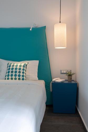 a bedroom with a bed with a blue headboard and a lamp at Acharavi Beach Hotel in Acharavi