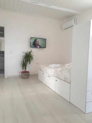 a white room with a bed and a tv on a wall at CASA DEL SOLE in Alcamo