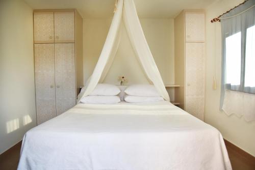 Una cama blanca con dosel en un dormitorio en Lydia House by Elefthia Syros, en Megas Gialos - Nites
