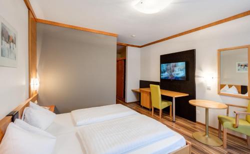 a bedroom with a bed and a desk and a table at Sporthotel Kurz in Oberpullendorf