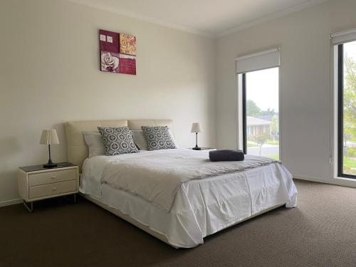 a white bedroom with a large bed and a window at London Park Resort in Narre Warren