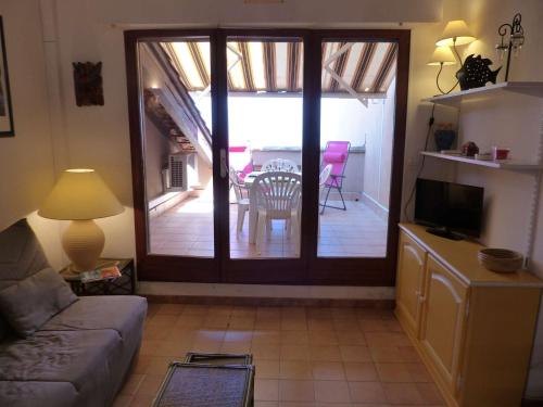 d'un salon avec une porte coulissante en verre et une table. dans l'établissement T1 Mezzanine Climatisé avec Terrasse et Parking - St Clair, Lavandou - FR-1-308-80, au Lavandou