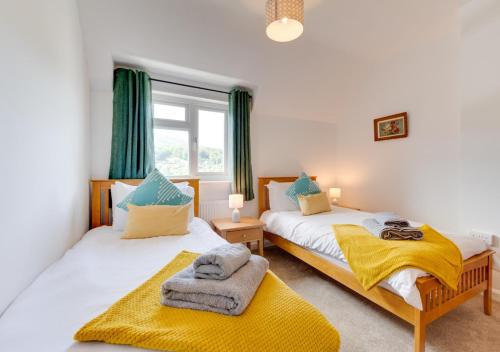 two beds in a bedroom with green curtains at Llety Heulog in Dolgellau
