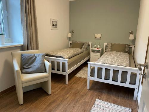 two beds and a chair in a room at Little Cottage in Visselhövede