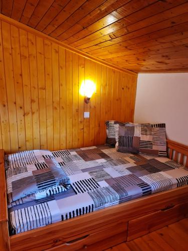 een bed in een kamer met een houten muur bij Къща за гости Каза Роза - Swiss Style Chalet Casa Rosa Guest House in Kyustendil