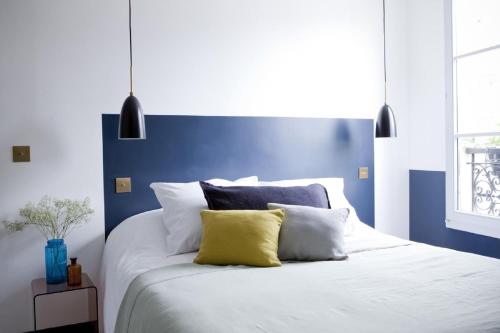 a blue and white bedroom with a bed with white pillows at Hôtel Henriette in Paris